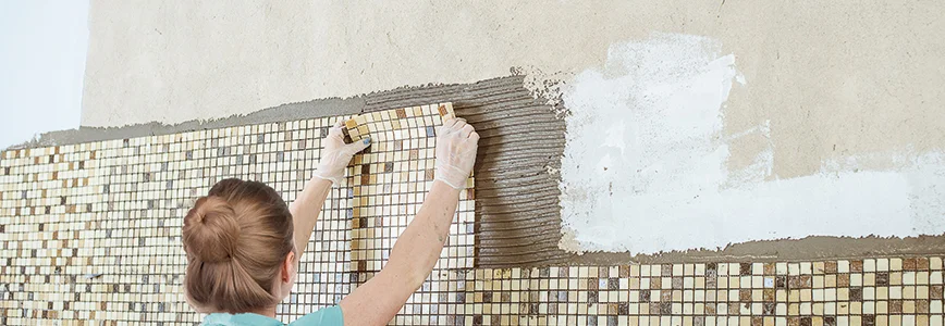 Person bringt Mosaikfliesen an